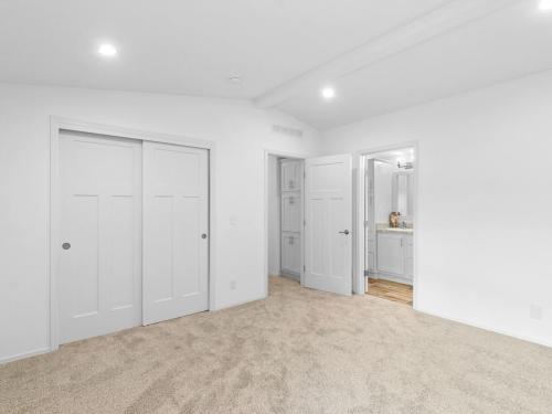 An empty bedroom with white walls and carpet.
