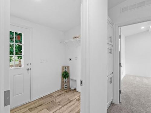 A white hallway with wood floors and a door.