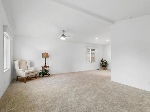 An empty living room with white walls and a fan.